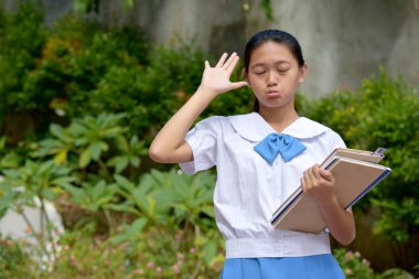 Bayan öğrenci okul kitaplarıyla komik suratlar yapıyor.