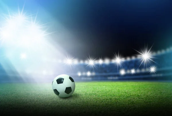 緑の草のスポット ライトとスタジアムにはサッカー ボール — ストック写真