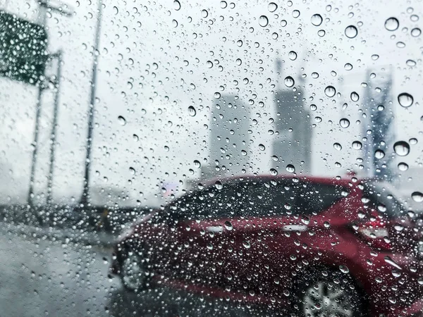 Raindrops on car glass at city in rainy day