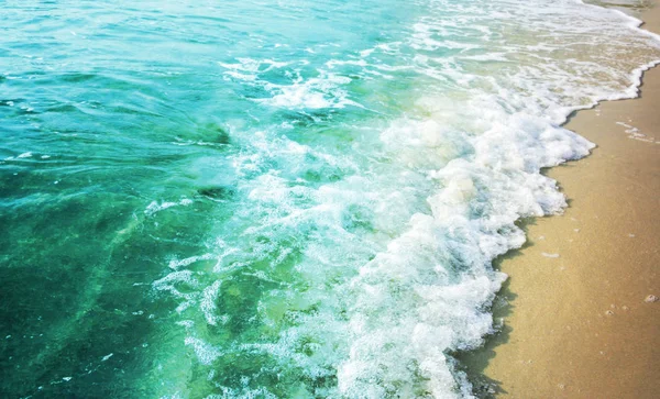 Sommer Hintergrund der türkisfarbenen Farbe Meer mit Welle auf dem Sandstrand — Stockfoto