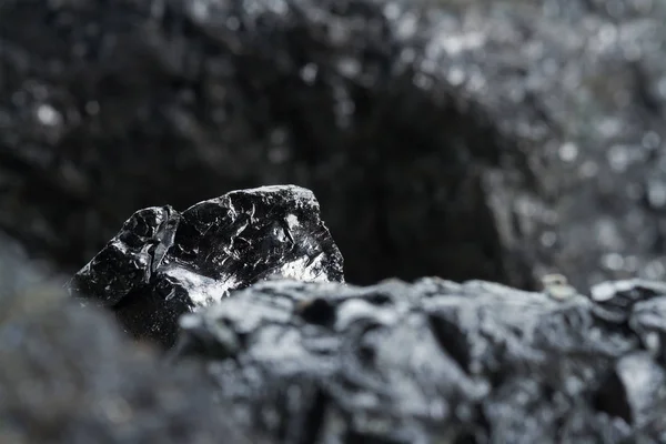 Primer plano de la mina de carbón negro con enfoque suave. Barra de carbón antracita sobre fondo oscuro. Barras de carbón negro natural para el fondo. Nuggets de carbón industrial de cerca — Foto de Stock