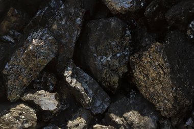 Kara kömür madeni yumuşak odaklı yakın plan. Karanlık arka planda antrakit kömür çubuğu. Arka plan için doğal siyah kömür çubukları. Endüstriyel kömür külçeleri