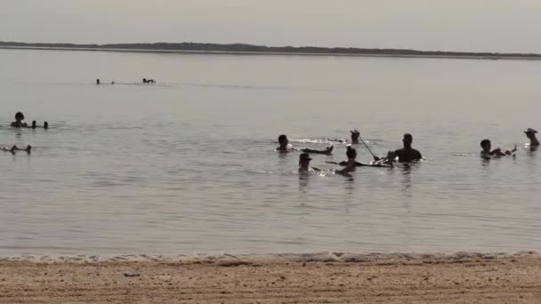死海で楽しんでいる人々 の映像 東とイスラエル共和国と西のヨルダン川西岸ヨルダンによって接される塩の湖 — ストック動画
