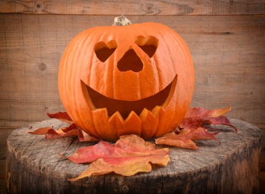 Cadılar Bayramı Balkabağı ve eski ahşap arka plan üzerinde sonbahar yaprakları.