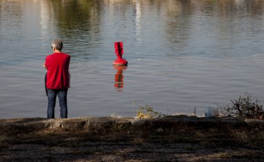 Kırmızı tişörtlü su kırmızı boya bakarak arkadan adam 