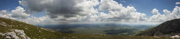 Bulutlu gökyüzü altında yeşil bir vadi üzerinde güzel dağ tepe manzaralı