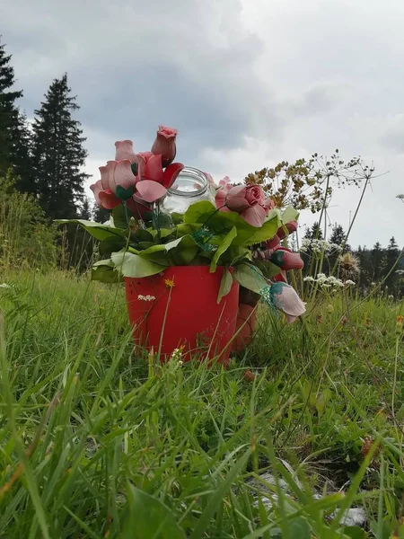 Bir çim alan bir kırmızı, plastik kova yapay, plastik çiçekler