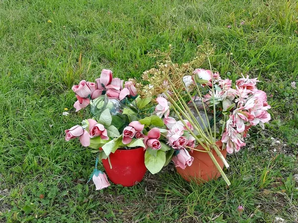 Bir çim alan bir kırmızı, plastik kova yapay, plastik çiçekler