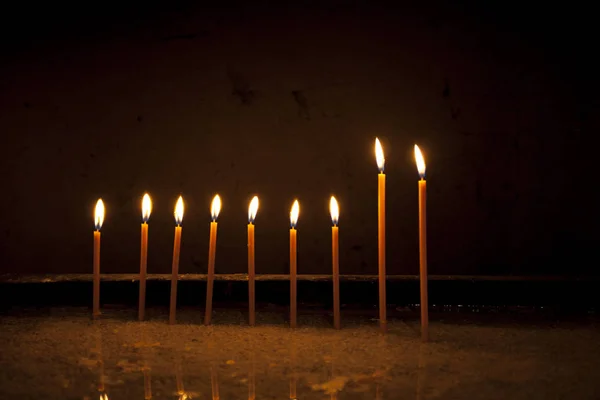 Kahverengi arka plan önünde dokuz yanan candels