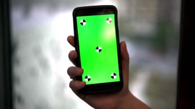 Bir Smartphone, yeşil ekran Video izlemek için hazır tutan kadın