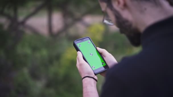 Young Man Holding Smartphone Met Lege Groen Scherm Buitenshuis — Stockvideo