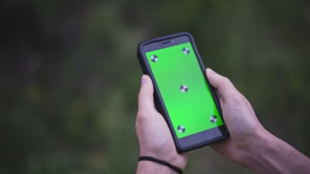 Jeune homme tenant Smartphone avec écran vert vide, en plein air   