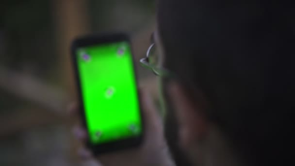 Jeune homme tenant Smartphone avec écran vert vide, en plein air   