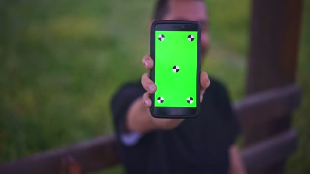 Jeune homme tenant Smartphone avec écran vert vide, en plein air   