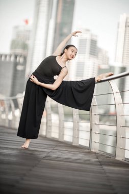 Güzel genç kız dans gökdelenlerin arka plana sahip siyah giyiyor şehirde 