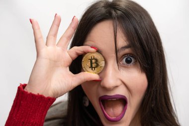 Süper heyecanlı başarılı kadın tutarak sağ gözü önünde bir Bitcoin