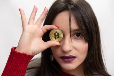 Ciddi kadın tutarak sağ gözü önünde bir Bitcoin
