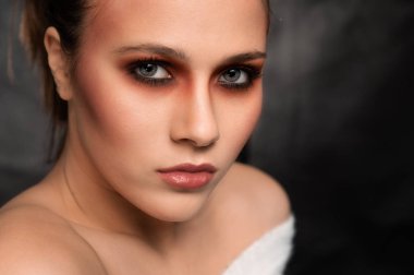 Güzel genç kadın, koyu gri arka plan üzerinde beyaz giyen vurdu