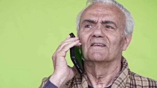 スマートフォンで話している高齢者の幸せな男は スローモーションビデオ 緑の背景をクローズアップ — ストック動画