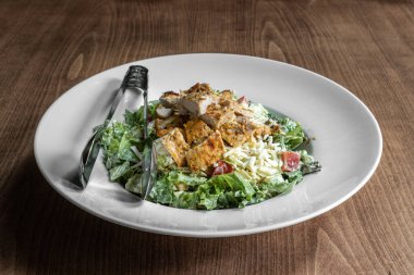 Lezzetli tavuk salatası, beyaz tabakta, ahşap bir masada.