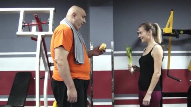 Şişko adam yeme hamburher bir spor salonu ve alaycı pırasa elleri içinde asılı bir sporcumuz bakın, bunlar gülümseyen ve lough birbirimize