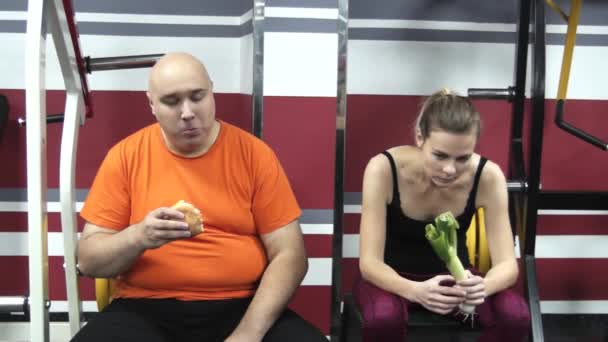 Gordo Divertido Hombre Está Comiendo Humburger Gimnasio Cerca Joven Hermosa — Vídeos de Stock