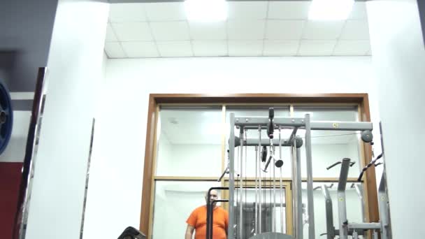 Hombre Gordo Guapo Con Una Camiseta Naranja Gimnasio Una Habitación — Vídeo de stock