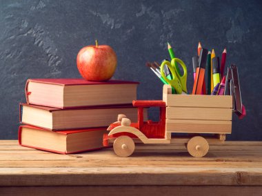 Oyuncak kamyon, kurşun kalem, okul malzemeleri ve ahşap masa üzerinde eski kitaplar ile okul kavramı geri