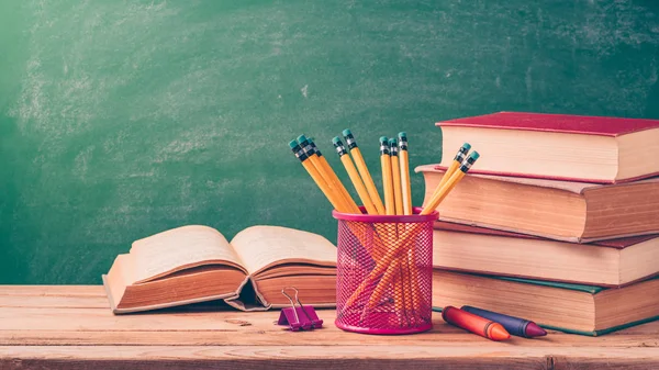 Geri okul ve arka plan için kalem kara tahta üzerinde eski kitaplar