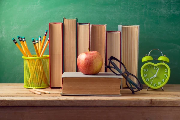 Geri okul ve arka plan için elma yazı tahtası üzerinde eski kitaplar