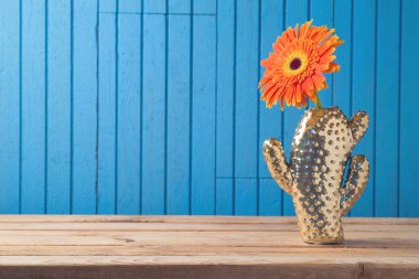 Gerbera papatya çiçek ahşap masa zemin üzerine altın kaktüs vazoda