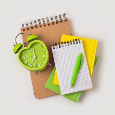 Okul kavramına defter, kalem ve çalar saat beyaz arka plan üzerinde geri. Yukarıdan görüntülemek