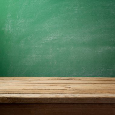 Boş ahşap masa yeşil kara tahta arka plan üzerinde. Geri okul kavramı