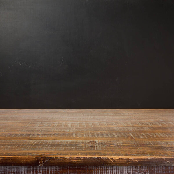 Empty wooden table over chalkboard background. Back to school concept