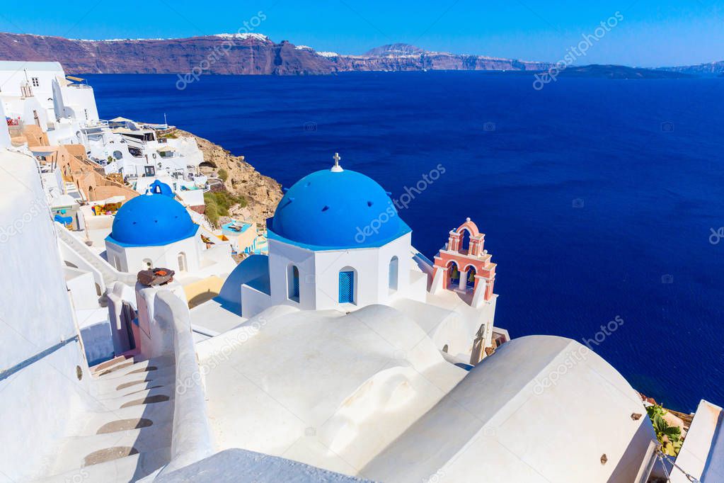 Santorini island, Greece. Oia town traditional white houses and churches with blue domes over the Caldera, Aegean sea.