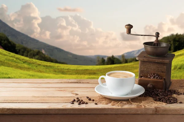 咖啡杯与研磨机在木桌之上在美丽的风景背景与拷贝空间 — 图库照片