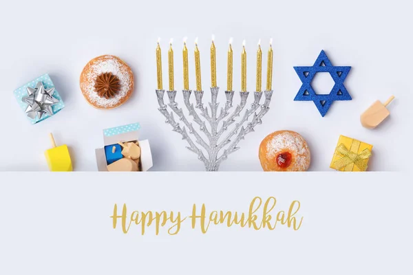 Jewish holiday Hanukkah banner design with menorah, sufganiyot and spinning tops on white background. Top view from above. Flat lay