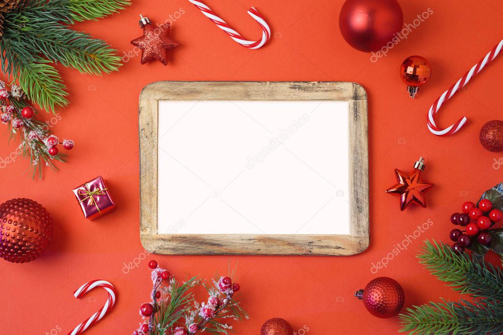 Christmas holiday background with photo frame, decorations and ornaments on red table. Top view from above. 