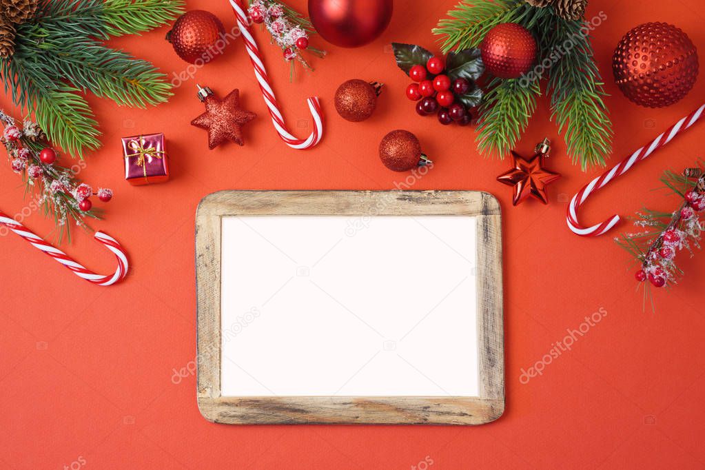 Christmas holiday background with photo frame, decorations and ornaments on red table. Top view from above. Flat lay