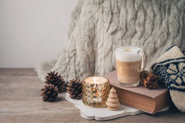 Hygge İskandinav tarzı konseptiyle latte macchiato kahve Kupası, mumlar ve kitap. Sıcacık kış veya Noel kompozisyon