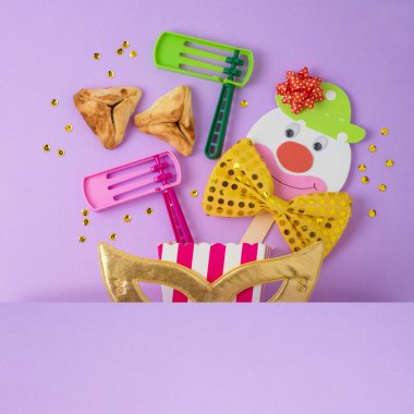 Jewish holiday Purim background with carnival mask, paper clown and hamantaschen cookies. Top view from above. Flat lay clipart