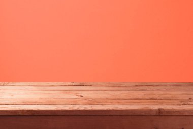 Mercan renk duvar arka plan üzerinde boş ahşap masa ile. Görüntü veya montaj ürün için alay