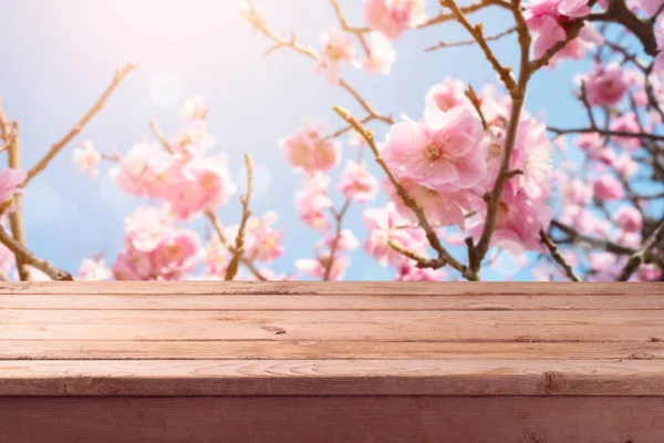 花桜背景のボケ味を持つ空木製テーブル 春のコンセプトです ディスプレイやモンタージュの製品のために模擬します — ストック写真