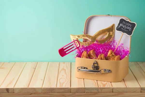 犹太节日普林背景与手提箱盒 狂欢节面具 噪音制造者和哈曼塔森饼干在木桌上 创意普林篮子的想法 — 图库照片