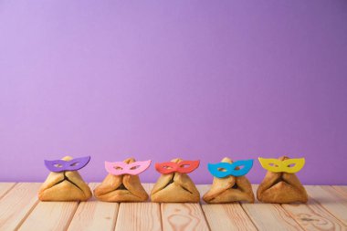 Yahudi tatil ahşap masa üzerinde şirin komik hamantaschen kurabiyeyle Purim arka plan. 