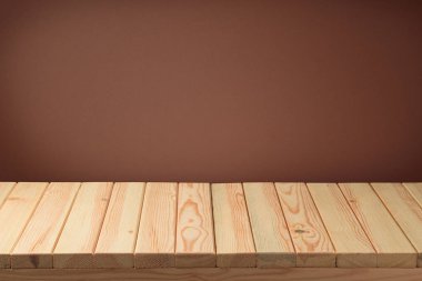 Boş ahşap masa kahverengi duvar arka plan üzerinde. Yiyecek standı, anahtar görsel düzeni veya yeni ürün ekran reklam için kullanılabilir