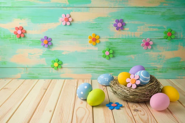 鳥の巣に卵をイースターの背景のイースター休暇と木製のテーブルの上に花の紙 — ストック写真