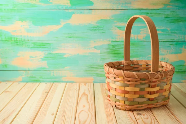 Empty basket on wooden table over colorful background.