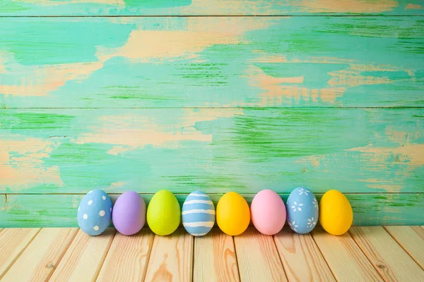 Decorazioni uova di Pasqua su tavolo di legno su sfondo colorato — Foto Stock