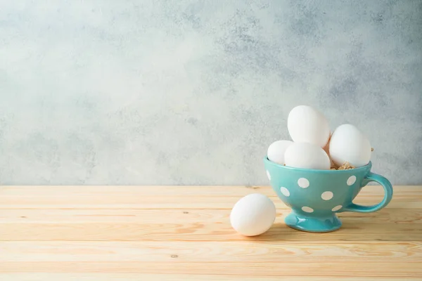 Fondo de Pascua con huevos frescos en taza sobre mesa de madera — Foto de Stock